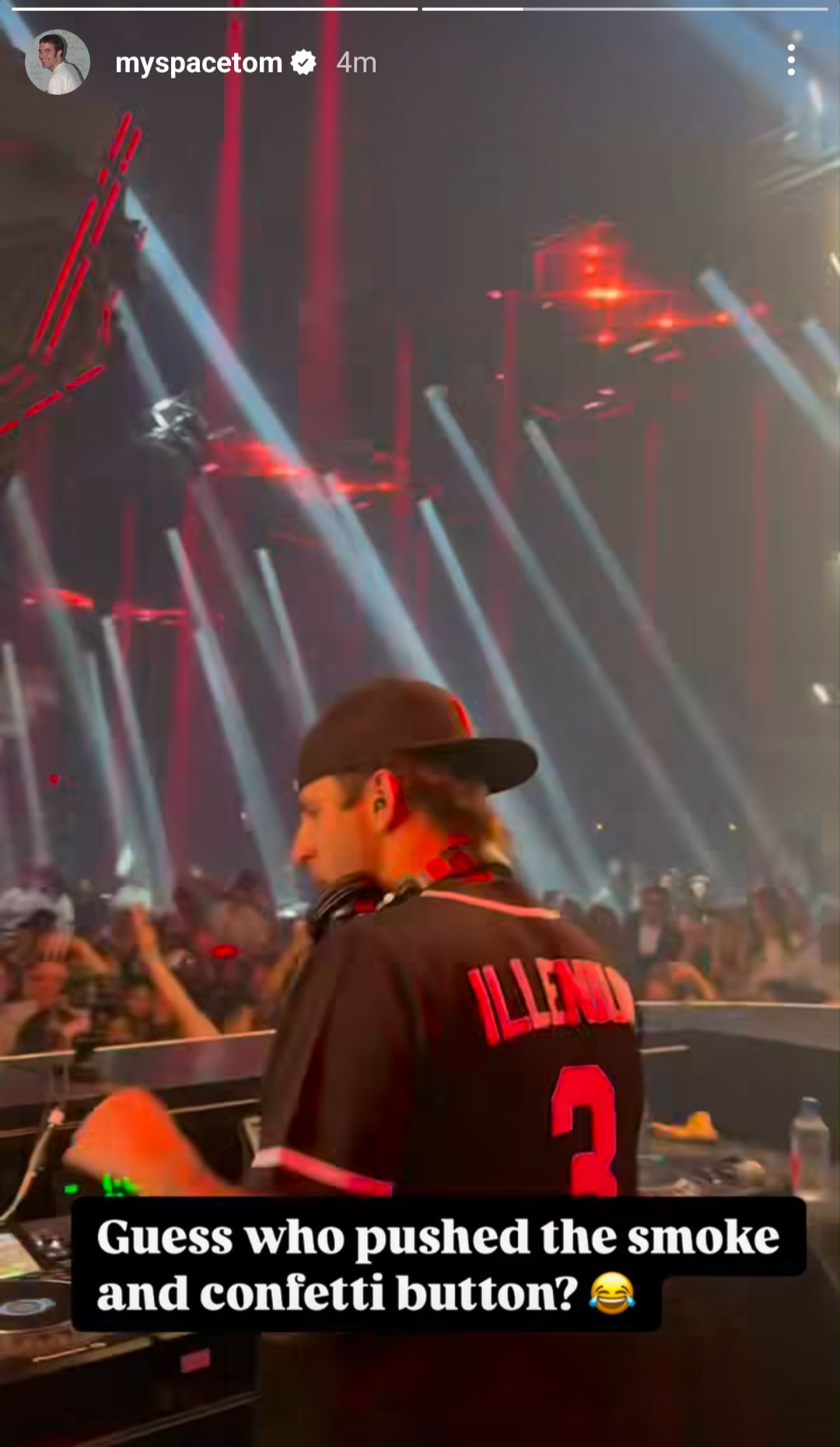 A DJ wearing a jersey with "Illenium" and the number 3 is performing on stage amidst a crowd with beams of light and smoke in the background. Overlayed text says "Guess who pushed the smoke and confetti buttons?"