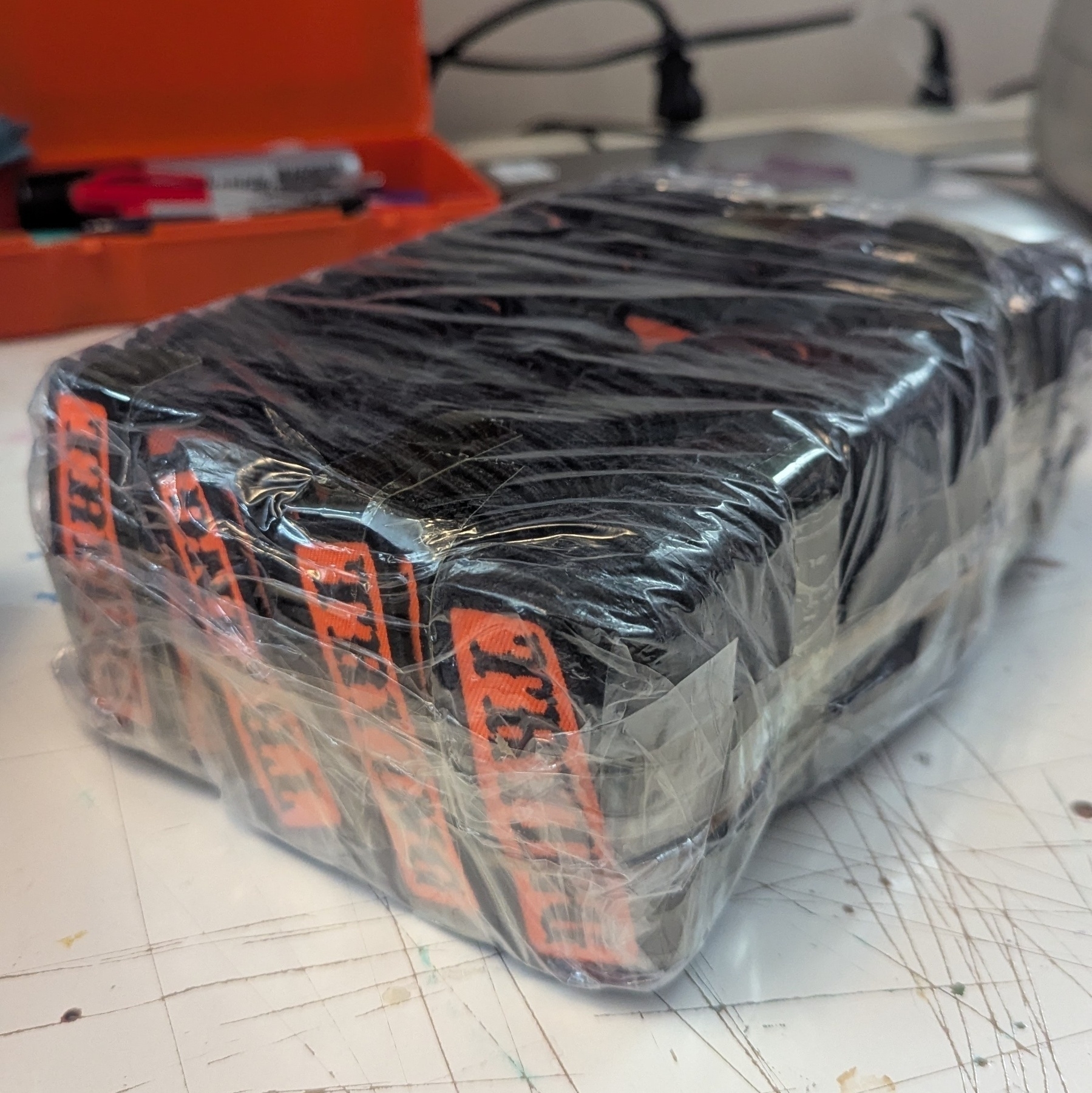 A shrink wrapped brick of orange and black patches that read TRYING