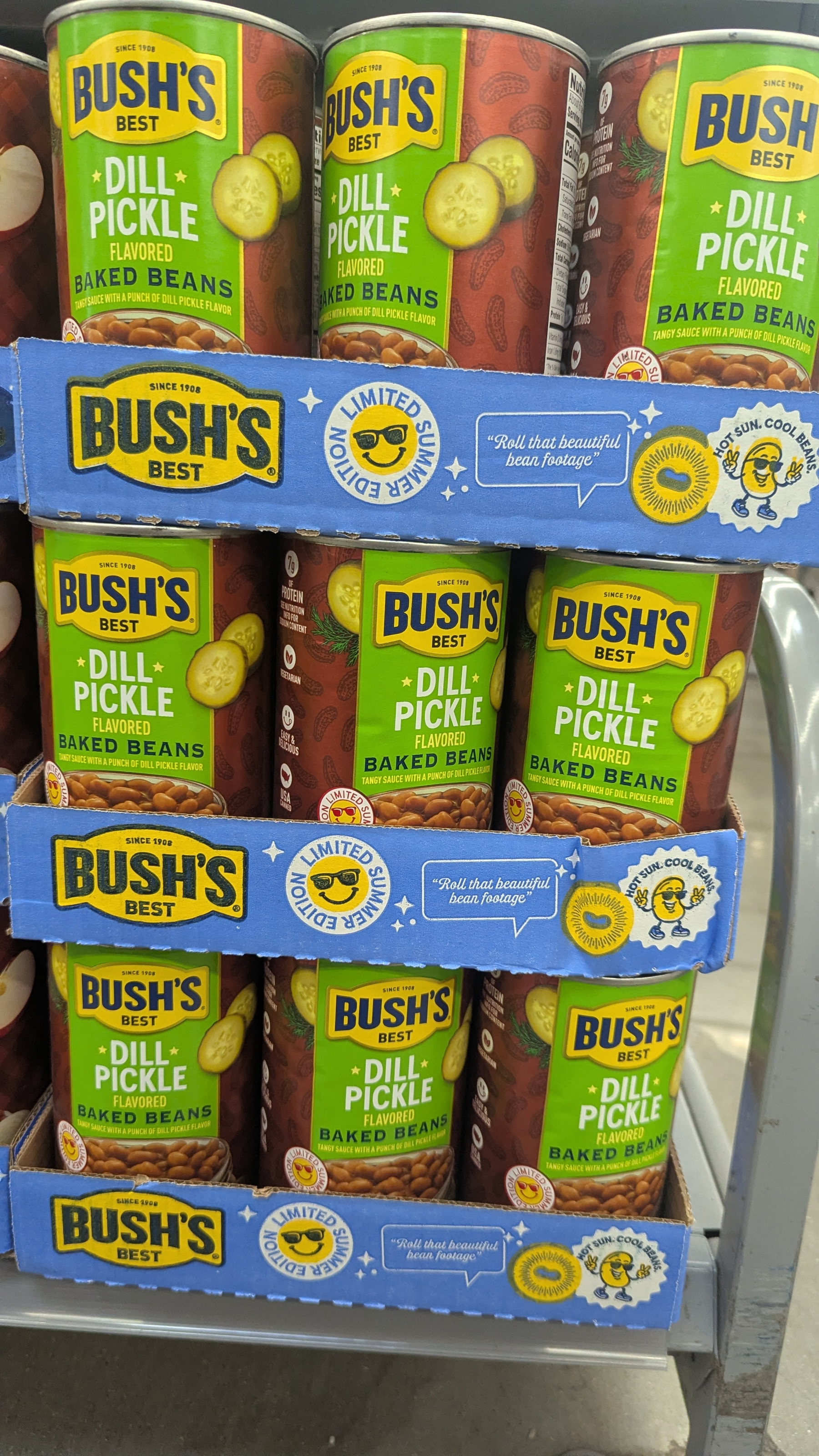 Cans of Bush's Best Dill Pickle flavored baked beans are stacked on a shelf
