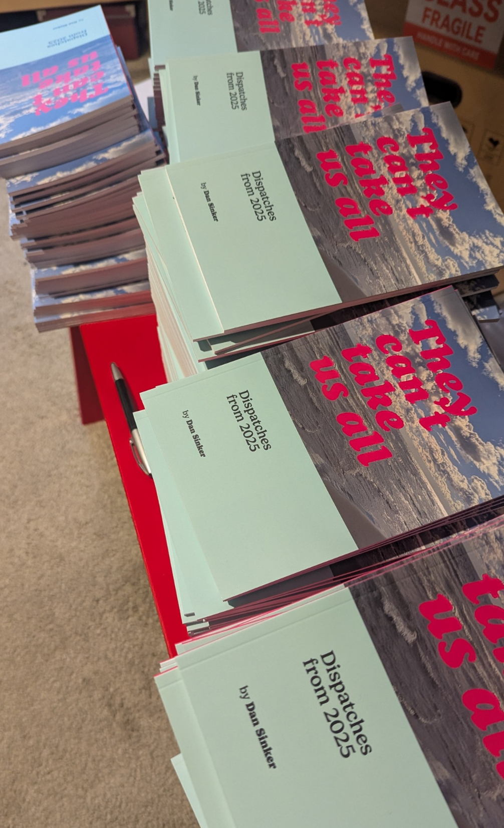 Stacks of zines are arranged on a table with a red surface.